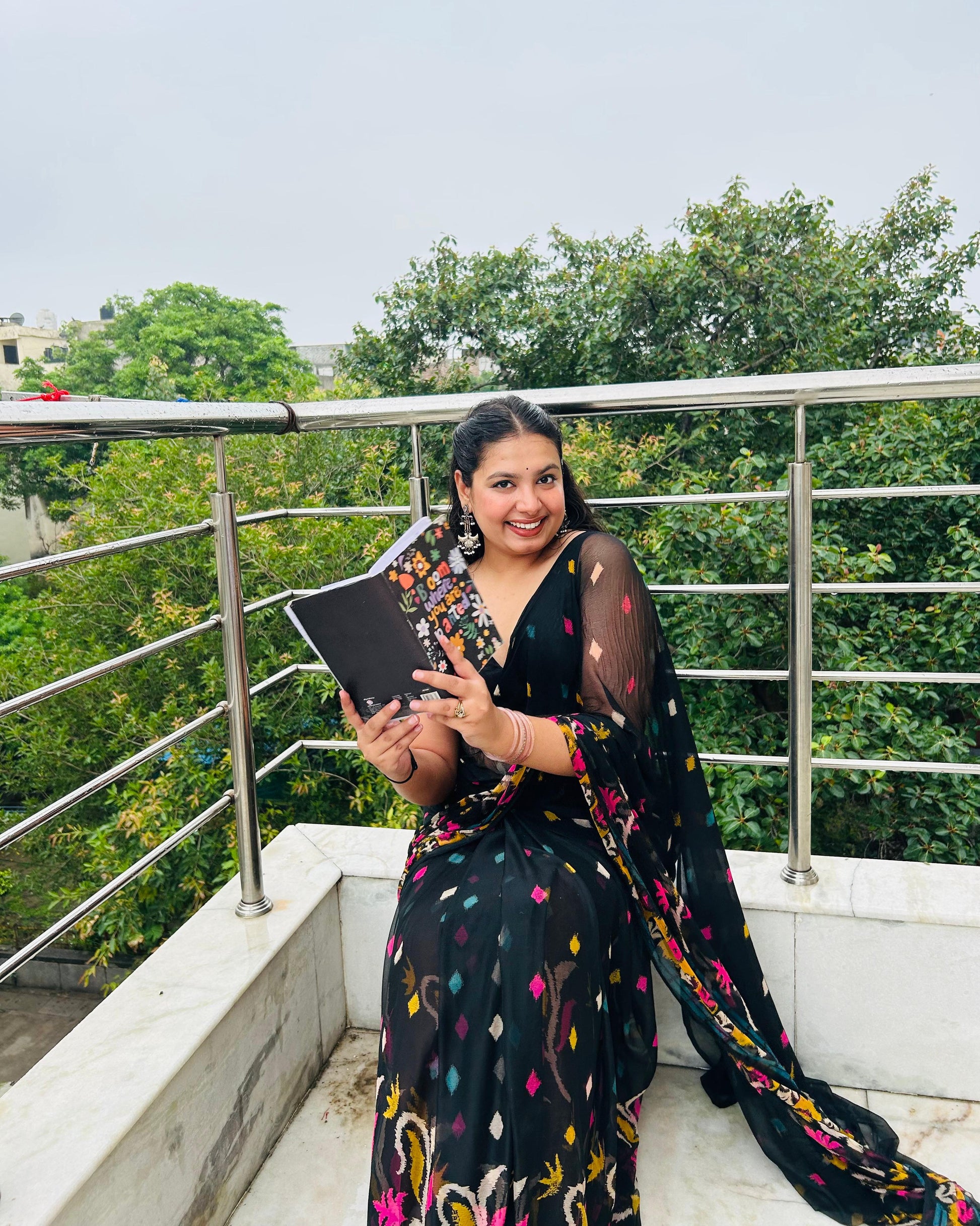 Woman holding a tablet on a balcony with greenery in the background